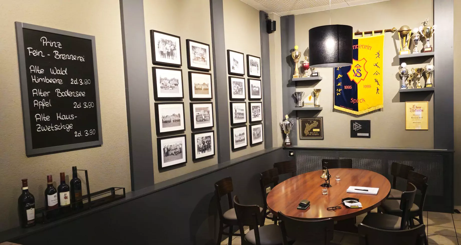 Restaurant von innen, Sitzplätze im Komm & Bleib, dekorierte Wand mit Fotos und Sportpokalen