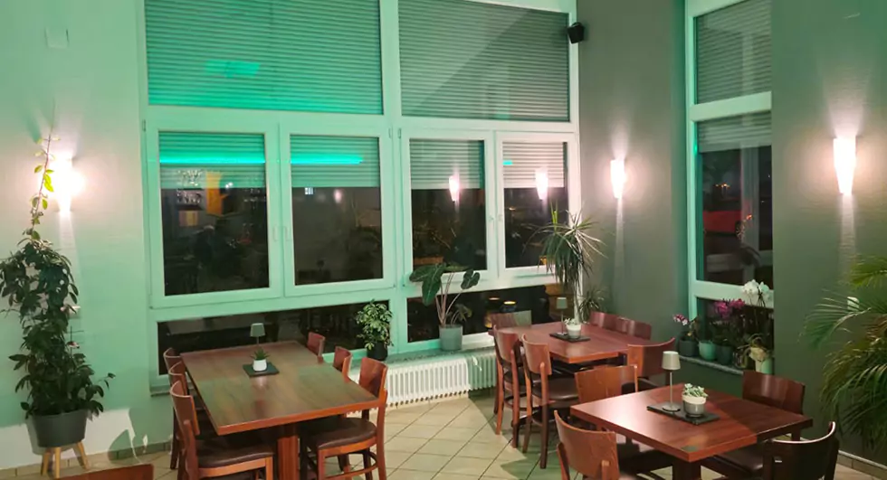 Tische und Stühle im Restaurant Komm & Bleib mit Fenstern
