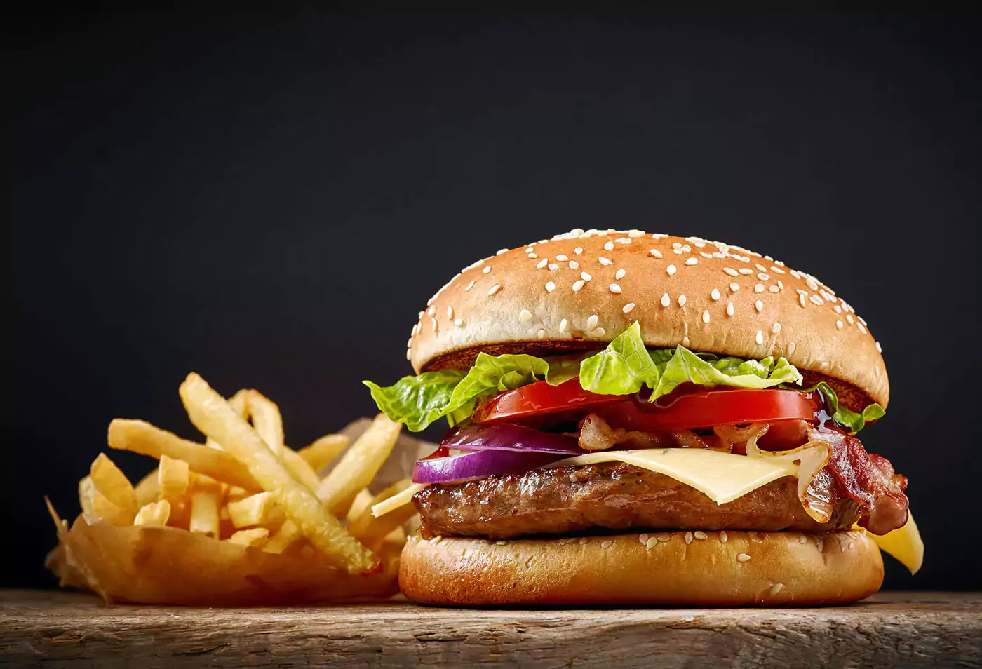 Leckerer hausgemachter Hamburger mit Käse, Bacon und knackigem Salat, dazu Pommes