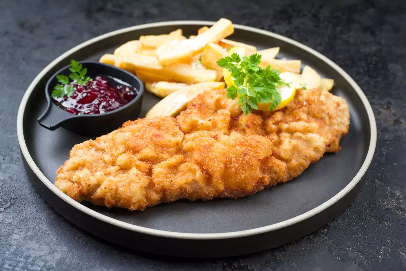 Gebratenes Wiener Schnitzel vom Kalb mit Pommes frites und Preiselbeersauce