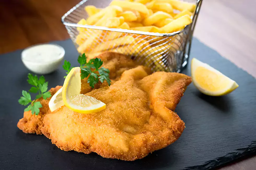 Wiener Schnitzel vom Kalb mit Zitronenscheibe mit Pommes frites und einem kleinen Schälchen Sour Creme